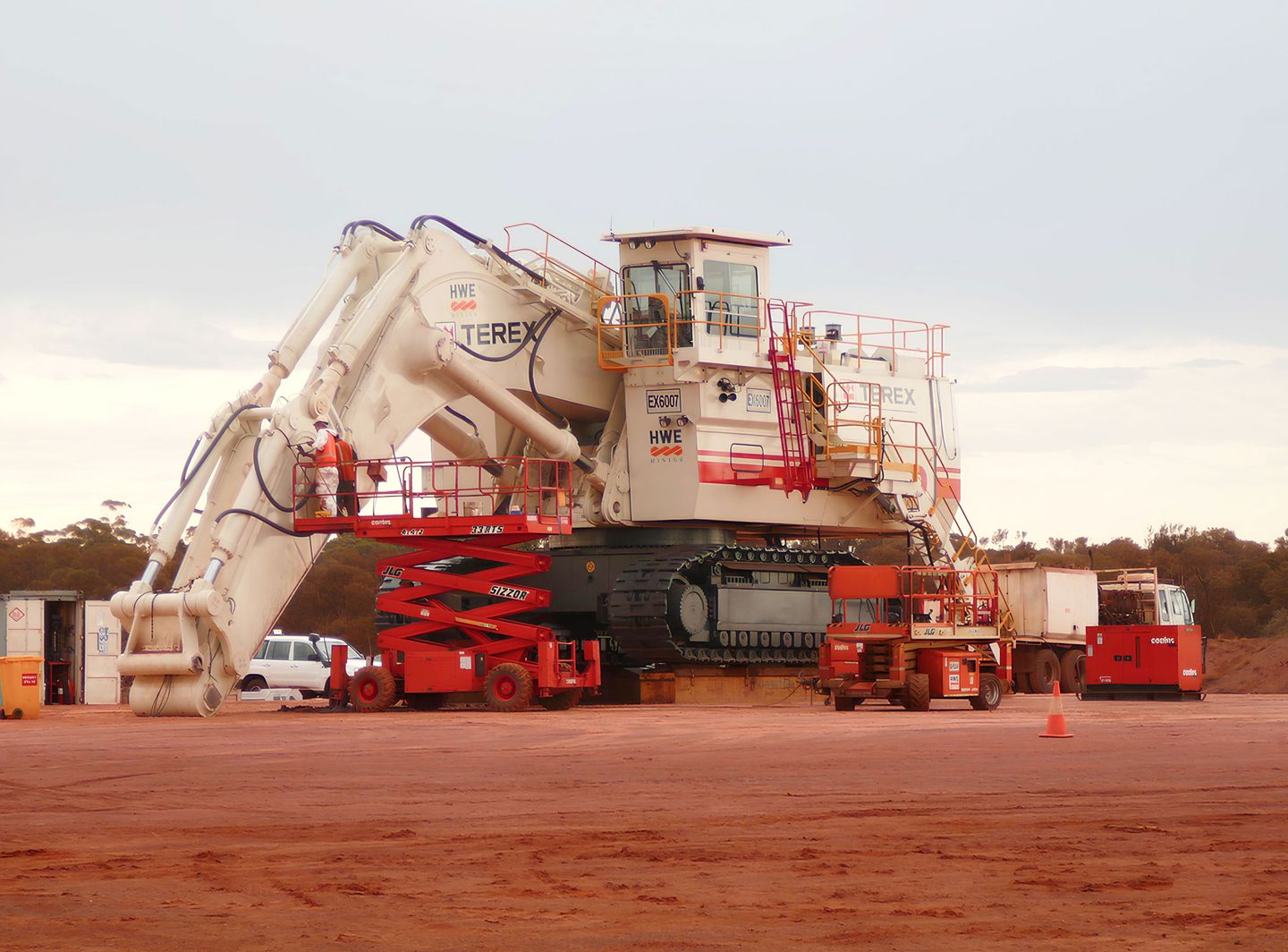 Ein großer Terex-Bergbaubagger auf rotem Erdboden mit Service-LKWs in der Nähe.